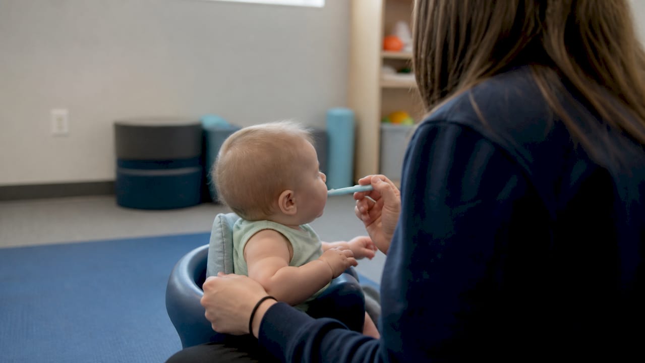 Speech therapist guiding infant oral motor exercise